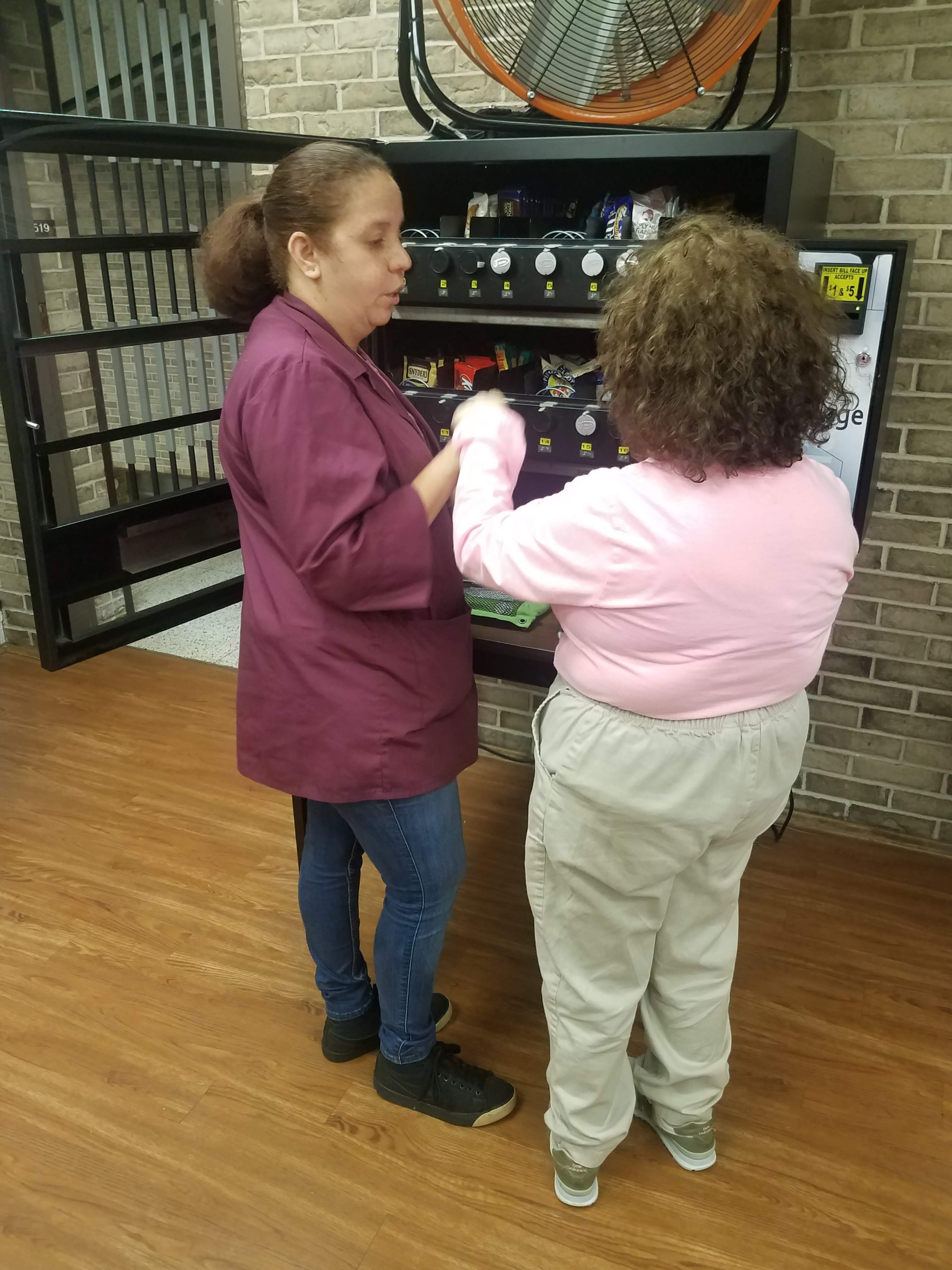 A destiny house resident and support staff restocking a vending machine.