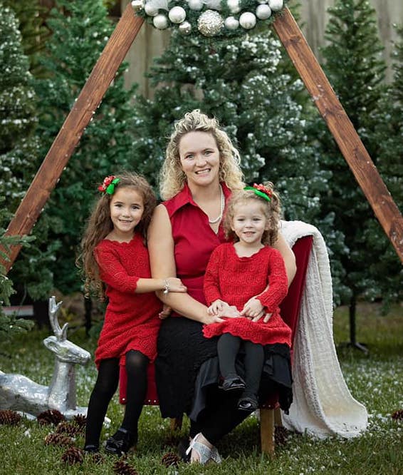 Tiffany Kohen with daughters in front of Christmas decorations.
