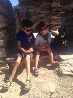 There are two young boys sitting outside on rocks with a rock structure around them