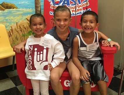 Three children sit in a large chair.