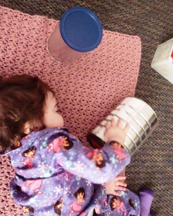 A child plays with a metal can.