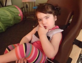 Child sits in a booster chair.