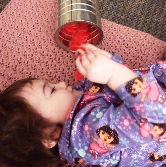 A child plays with discs that are inside of a can.