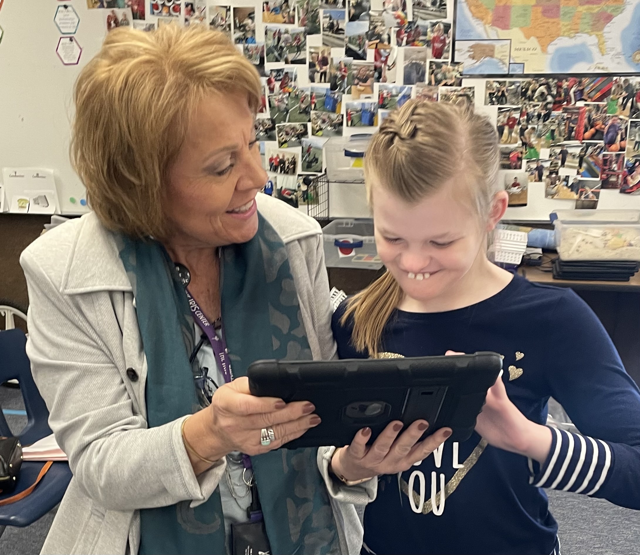 A teacher and a girl look at an electronic tablet together.