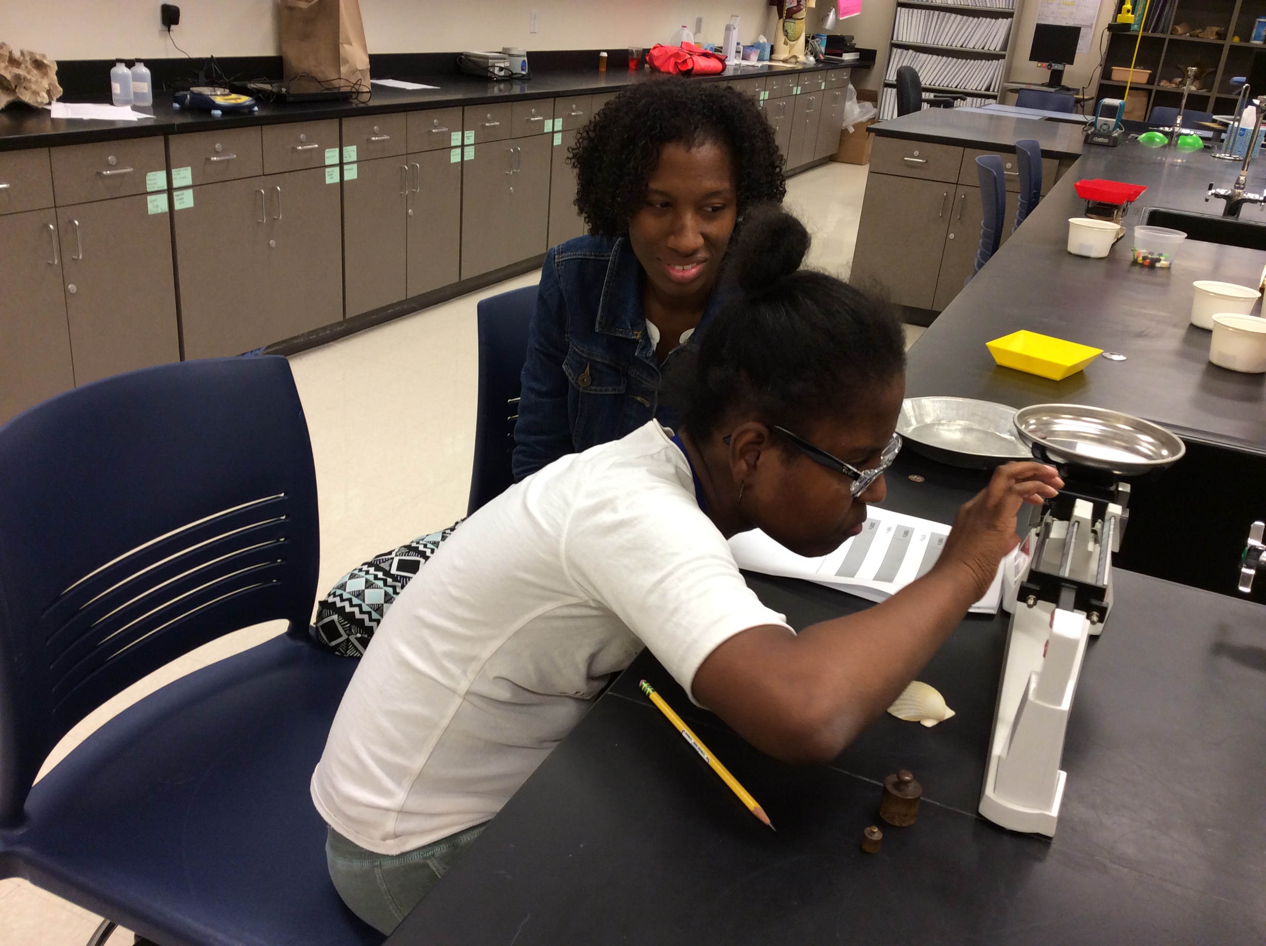 Young girl sits with teaching assistant doing a science project.