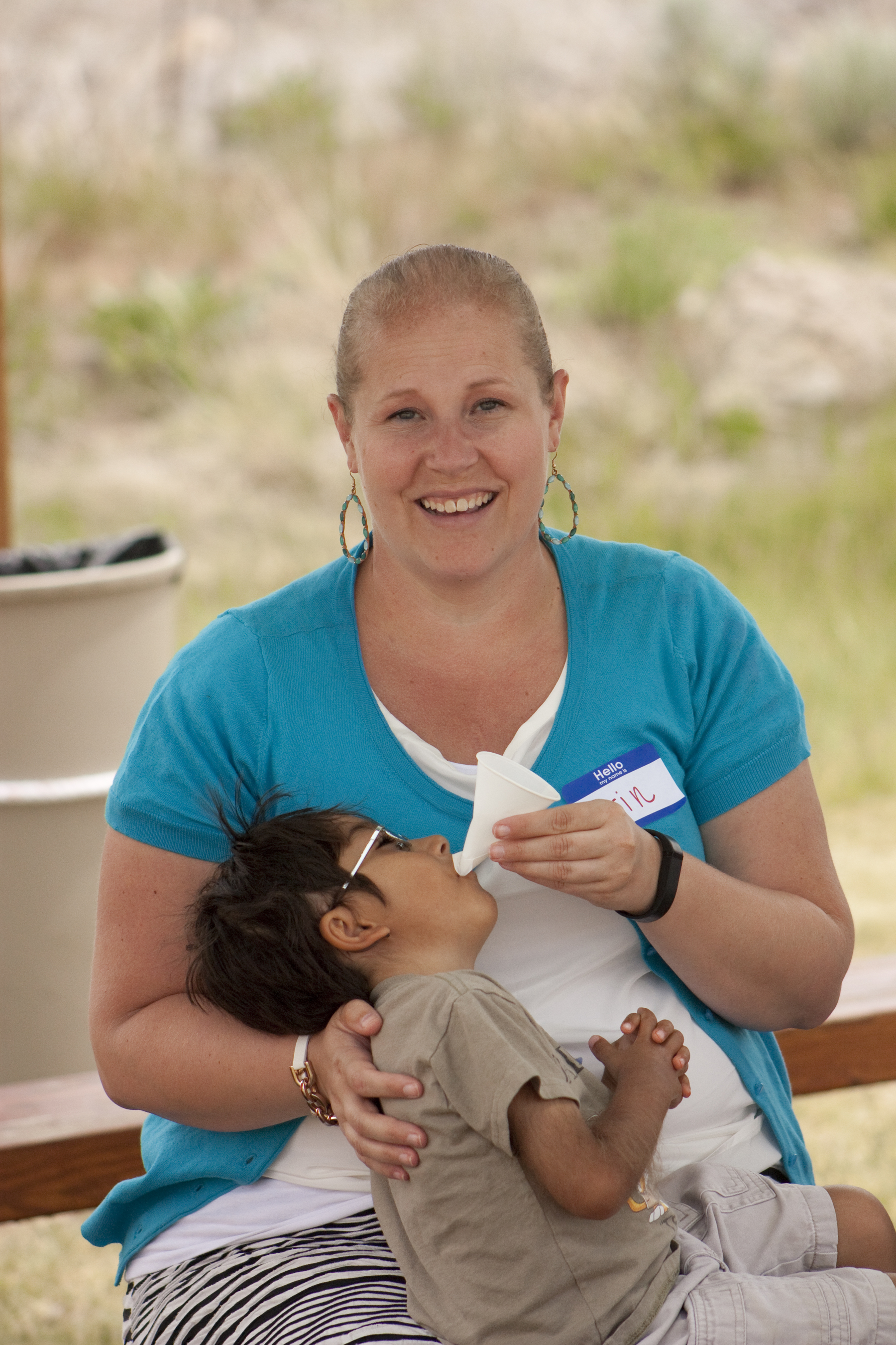 Erin helps a student take a drink of water during break time at a summer event.