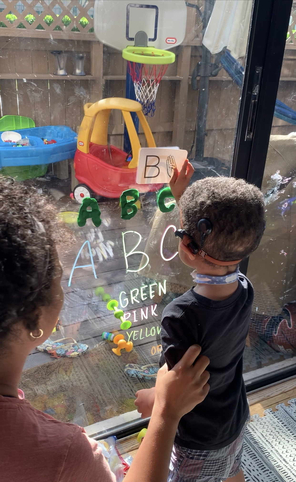 Jaxson identifies letters of the alphabet through stickers placed on a window.