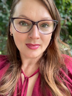 A woman with long brown hair and glasses.