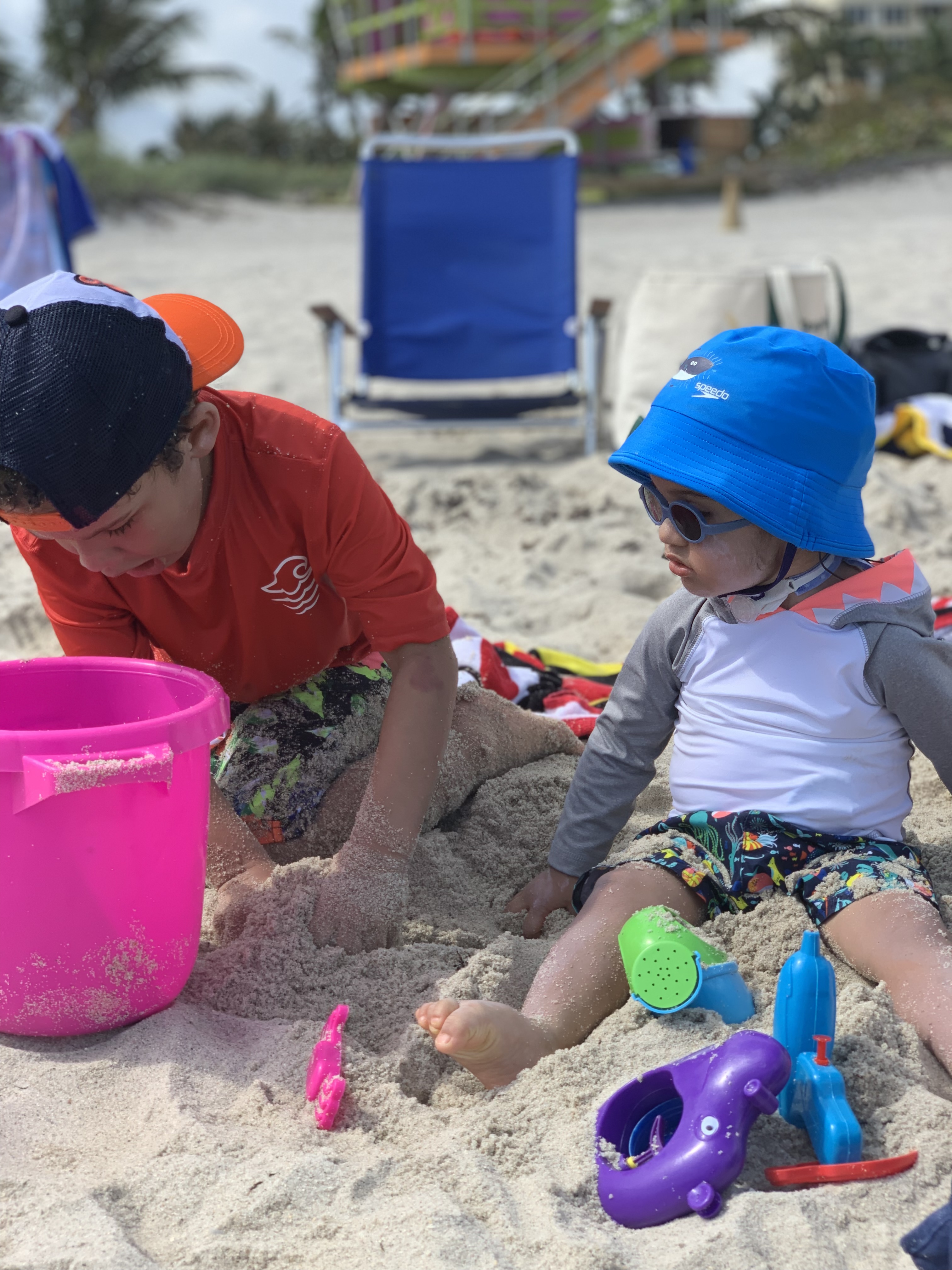 Jaxson and his brother play with toys in the sand at the beach.