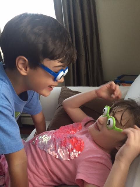Two children wear big eye toy glasses.