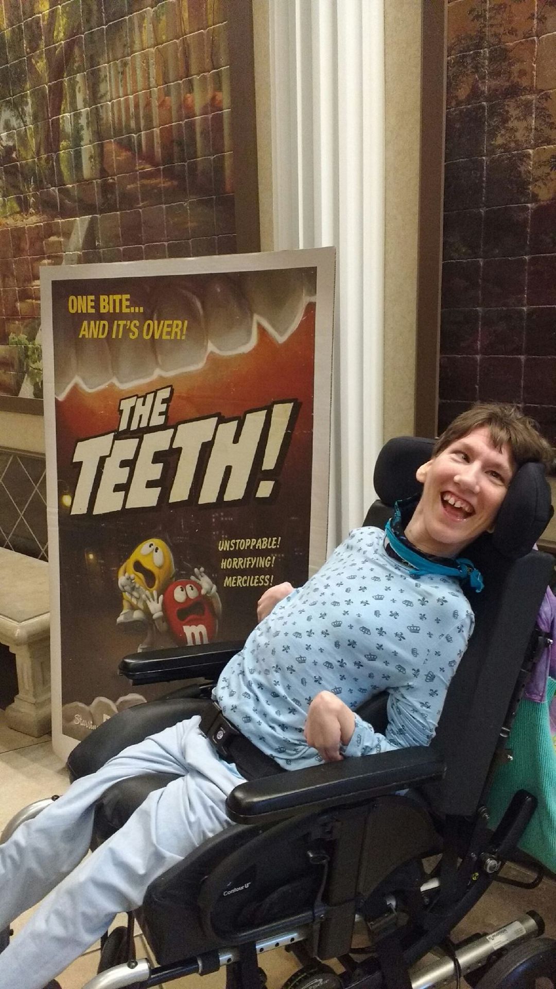 Jackie is in front of a sign with M&M's that says "The Teeth!"