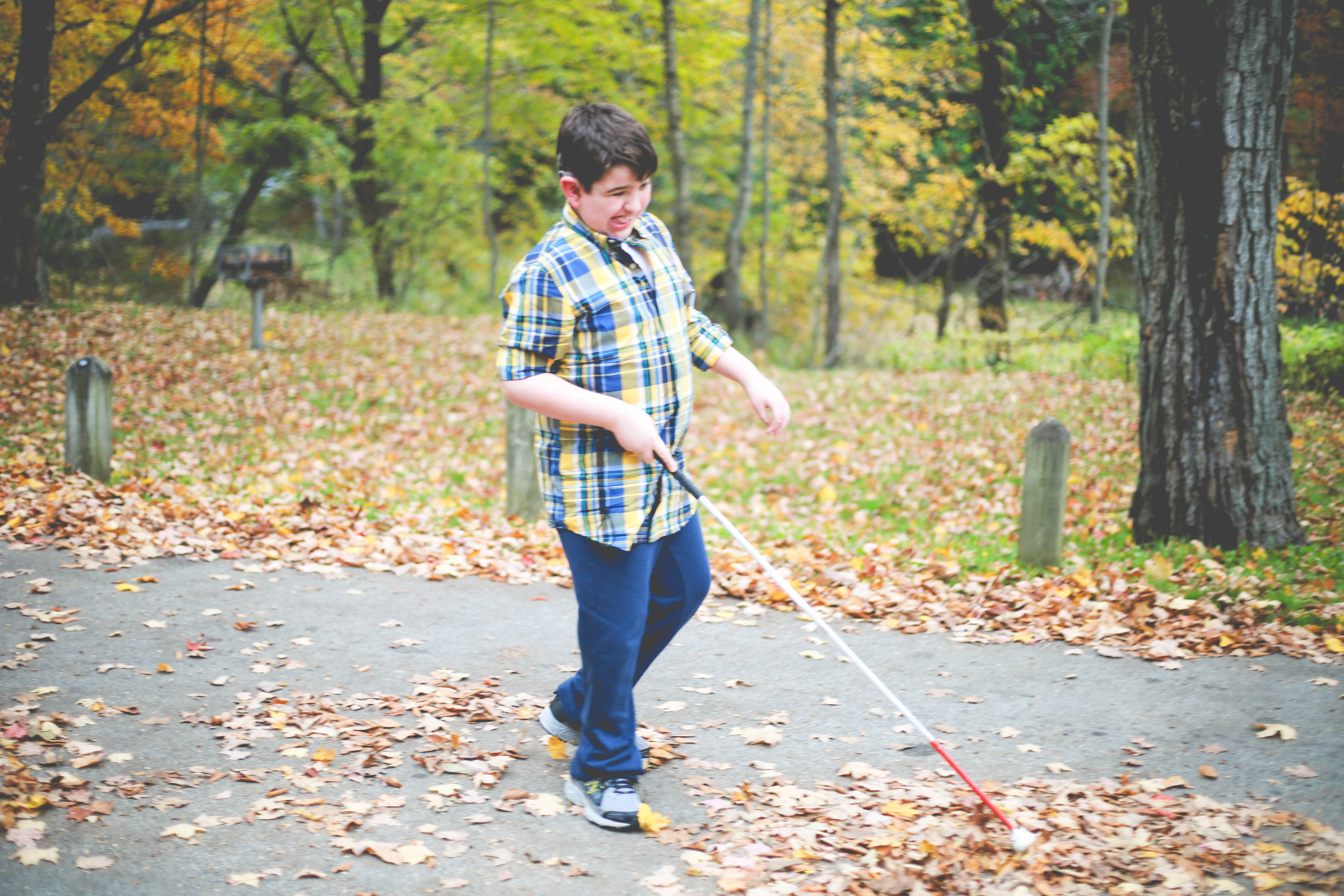 Liam walking with a cane next to a pile of leaves.