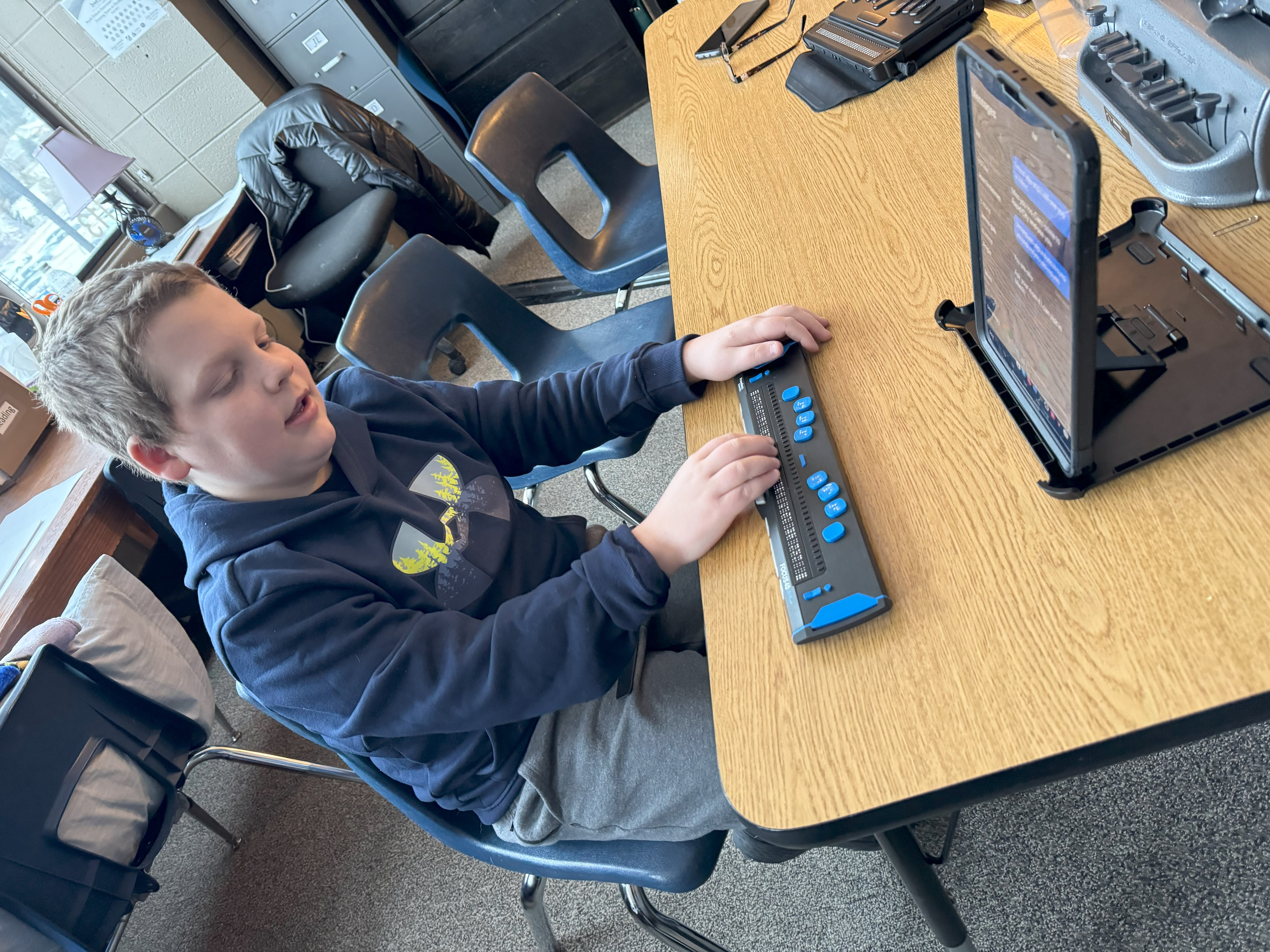 A teen uses a braille keyboard and a tablet to do schoolwork.