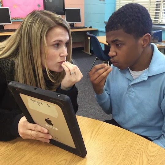 Young man and teacher signing looking at iPad.