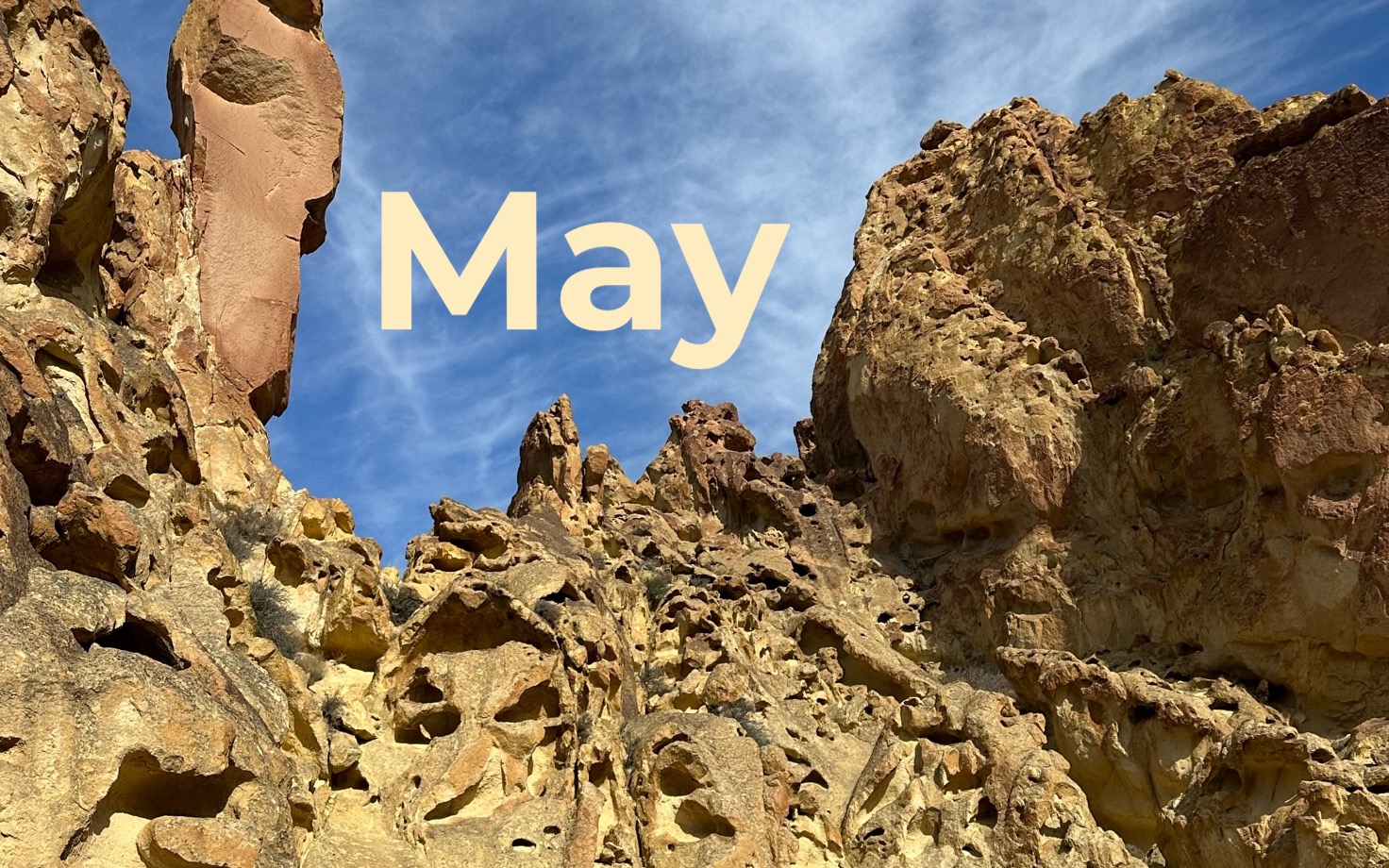 A rocky landscape of Oregon with blue sky behind and the word "May".