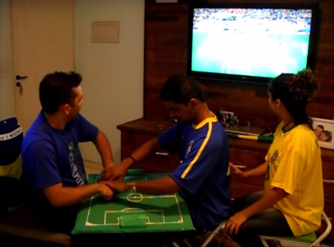 Young deaf-blind man watches soccer through a tactile board.