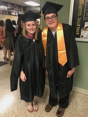 A graduation photo of a young adult student and a teacher. Both are wearing caps and gowns.