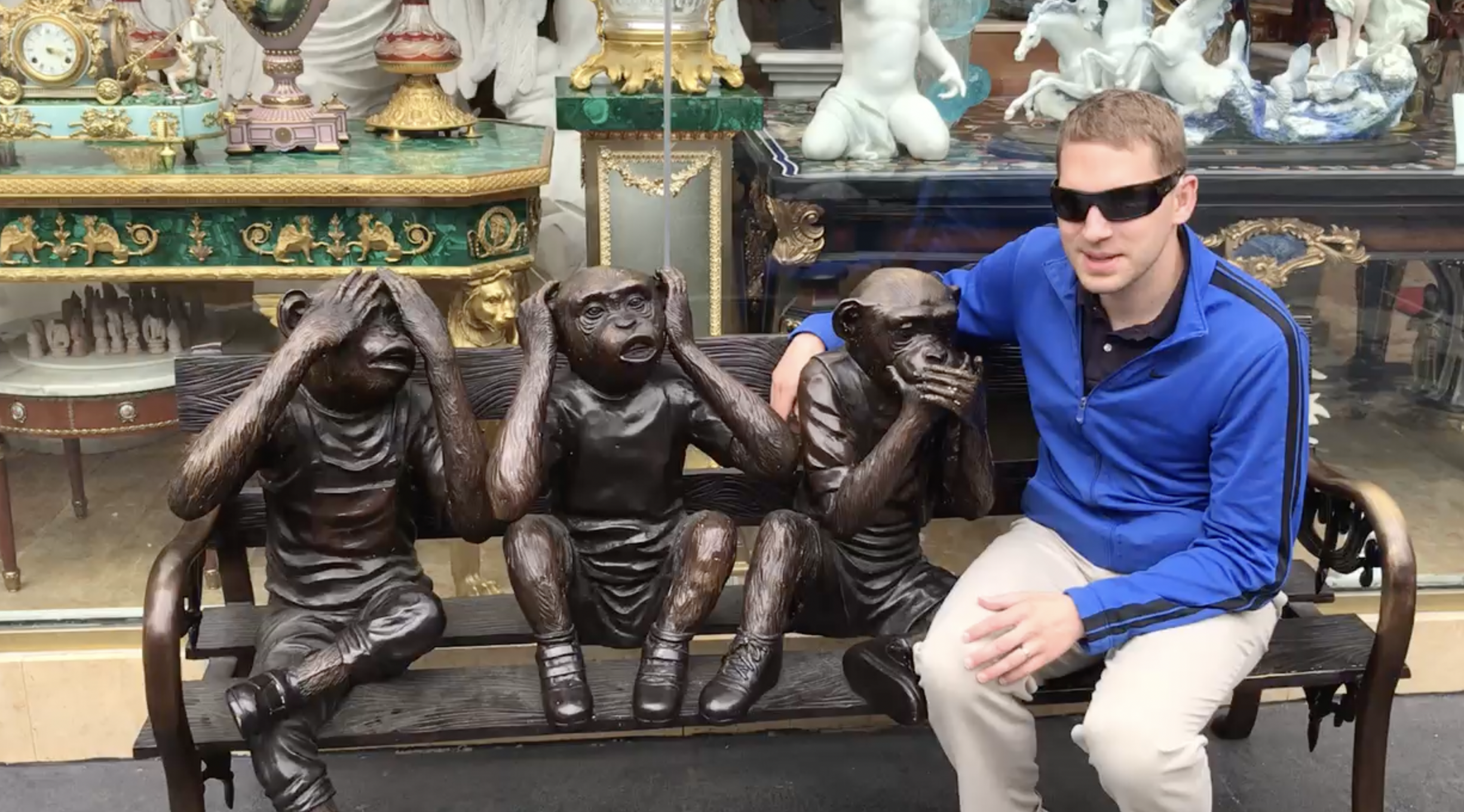 Jason Corning sitting with three statue monkeys. One monkey is covering his ears. One monkey is covering his eyes. One monkey is covering his mouth.