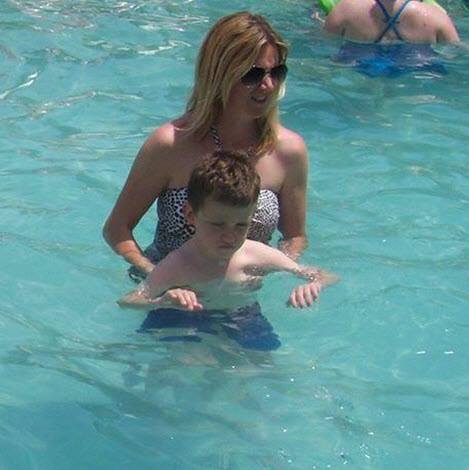 There is a woman in a pool holding Ryan