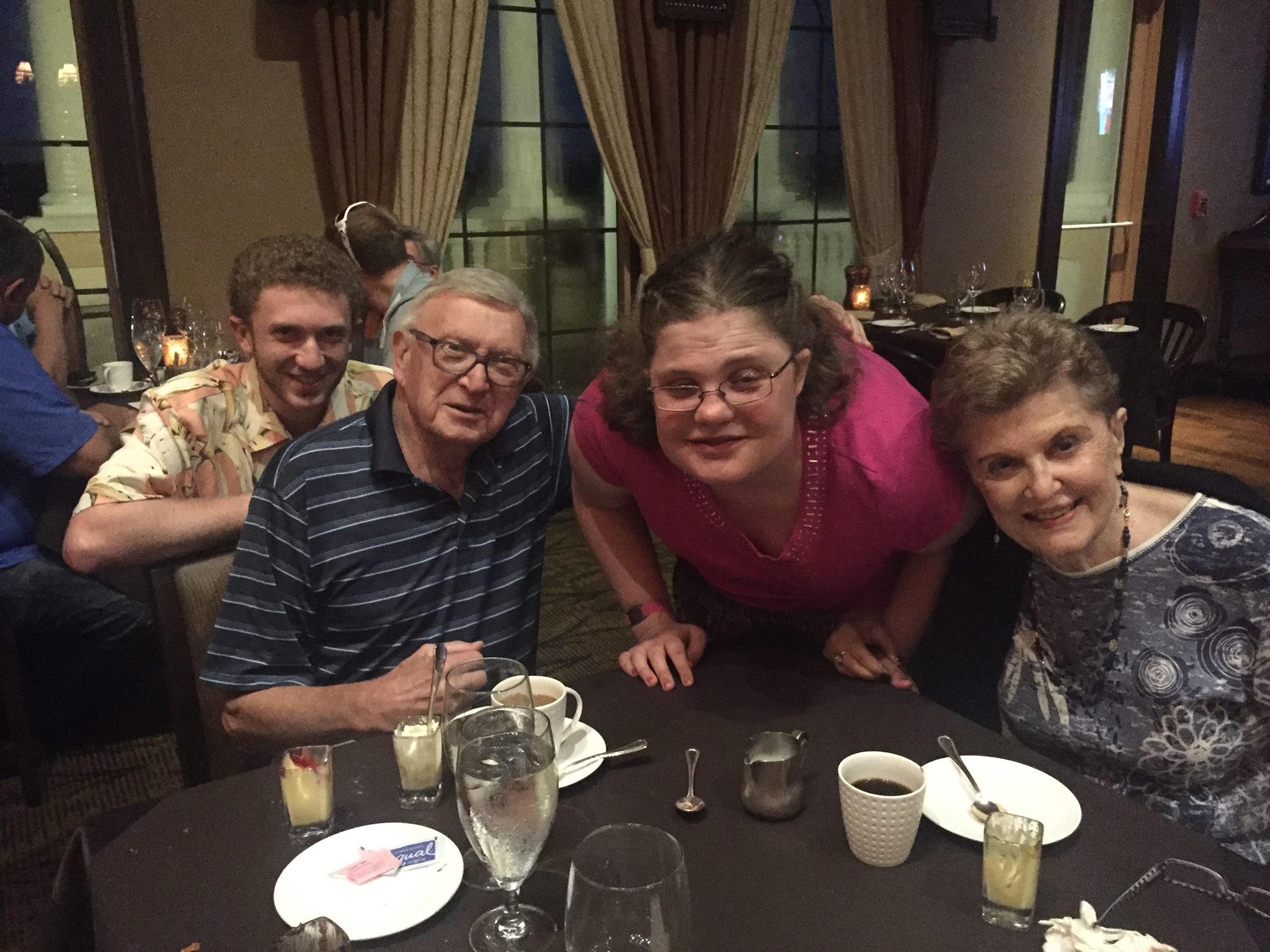 There are four people at a table with drinks and plates