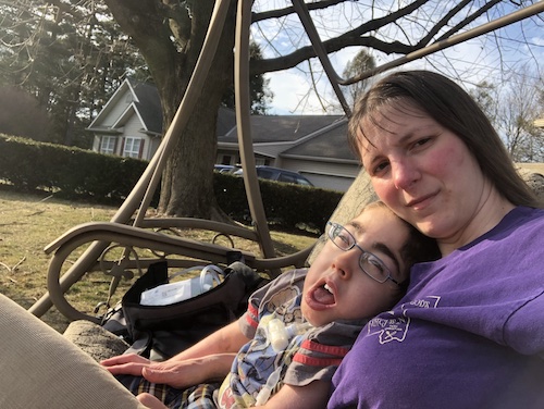 Ben and mom sit in a couch swing.
