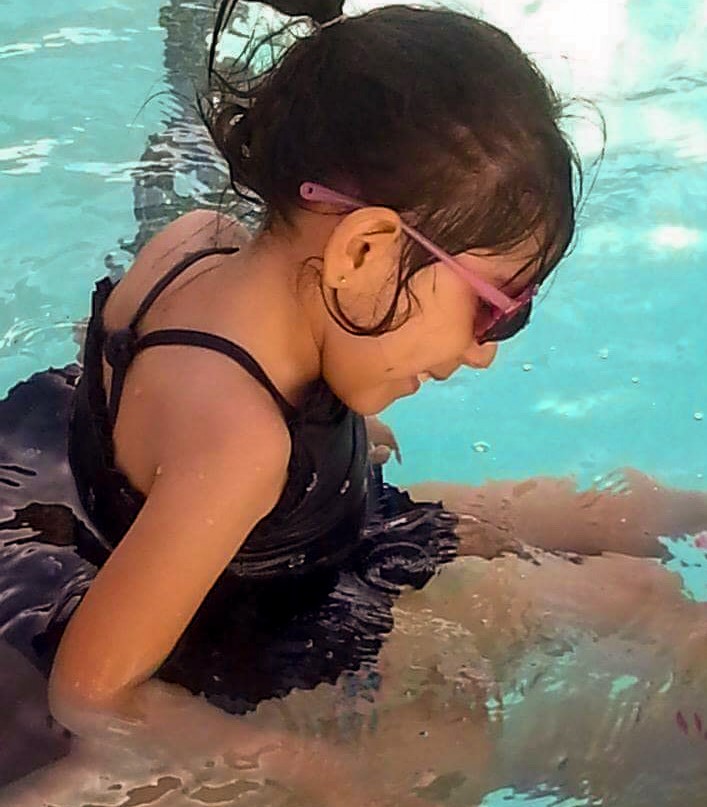 A girl sitting in a swimming pool.