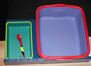 A small bin with a spoon to the right of a larger empty bin.