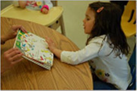 child sitting at table looking at picture book