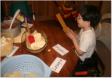 child sitting at table with labeled cooking ingredients in front of him