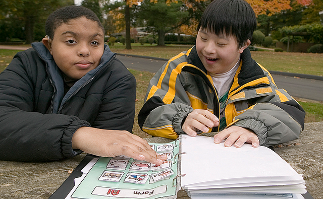 Two boys, sitting at a picnic table, working through a literacy book.