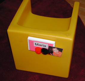 A booster seat with a name label and picture of maria