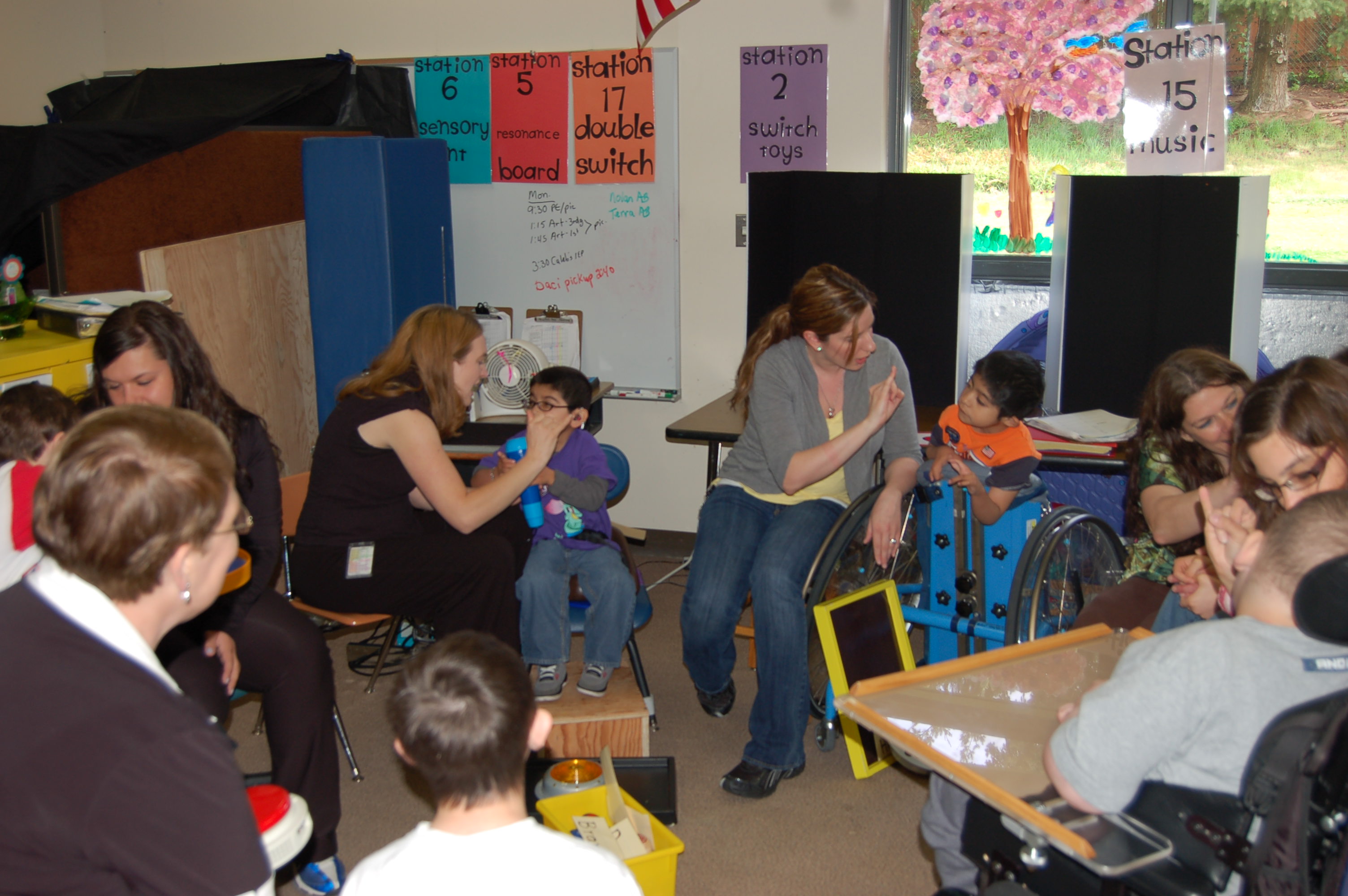 Circle time in a classroom of students with disabilities. There are five children, each with a one-to-one aide.