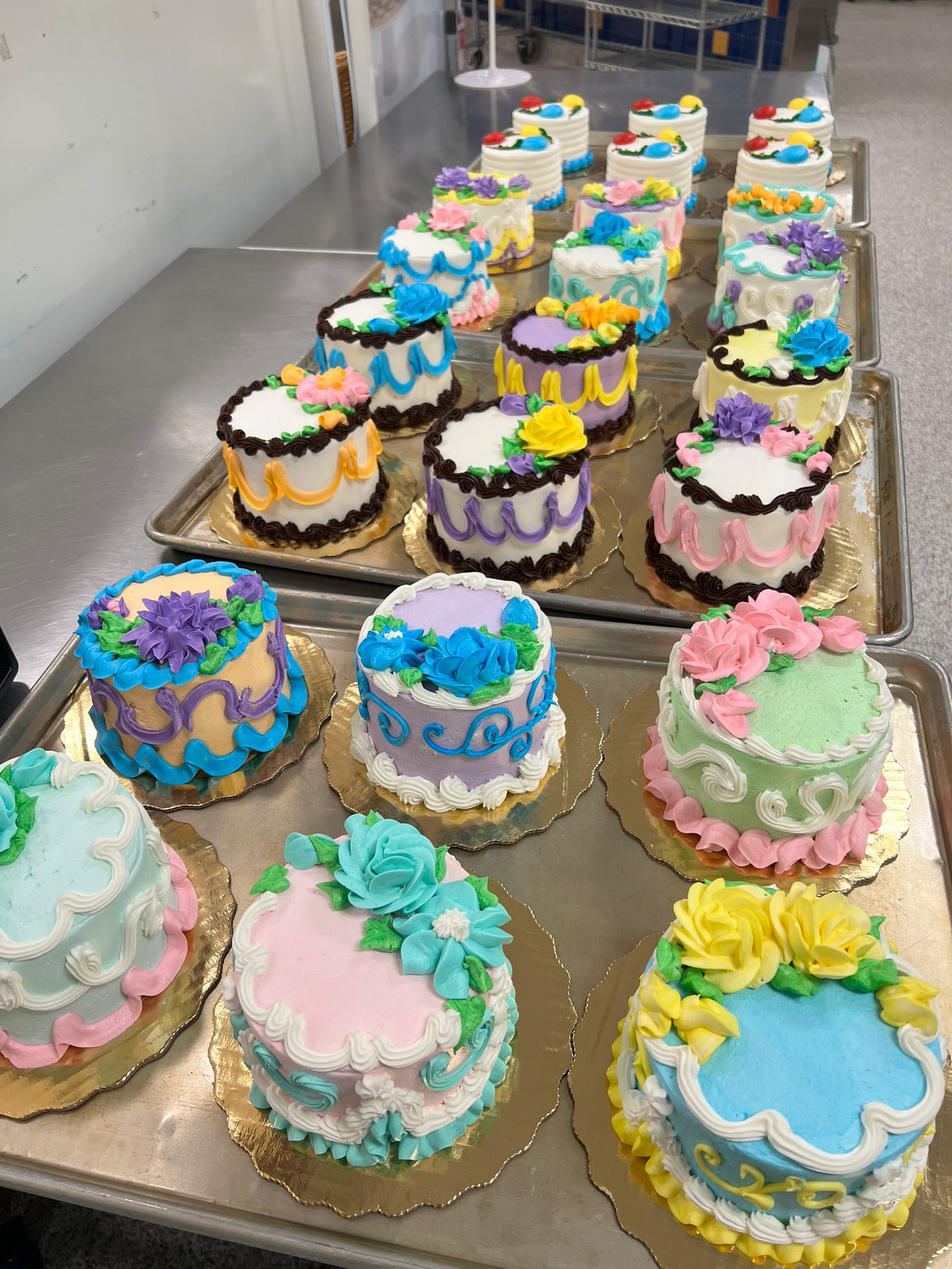 Multiple cakes decorated with colorful icing and flowers.